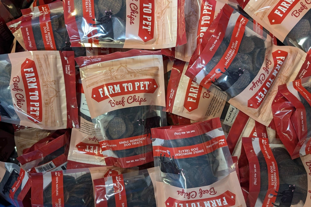 A pile of Farm to Pet Beef Chip bags on a table.