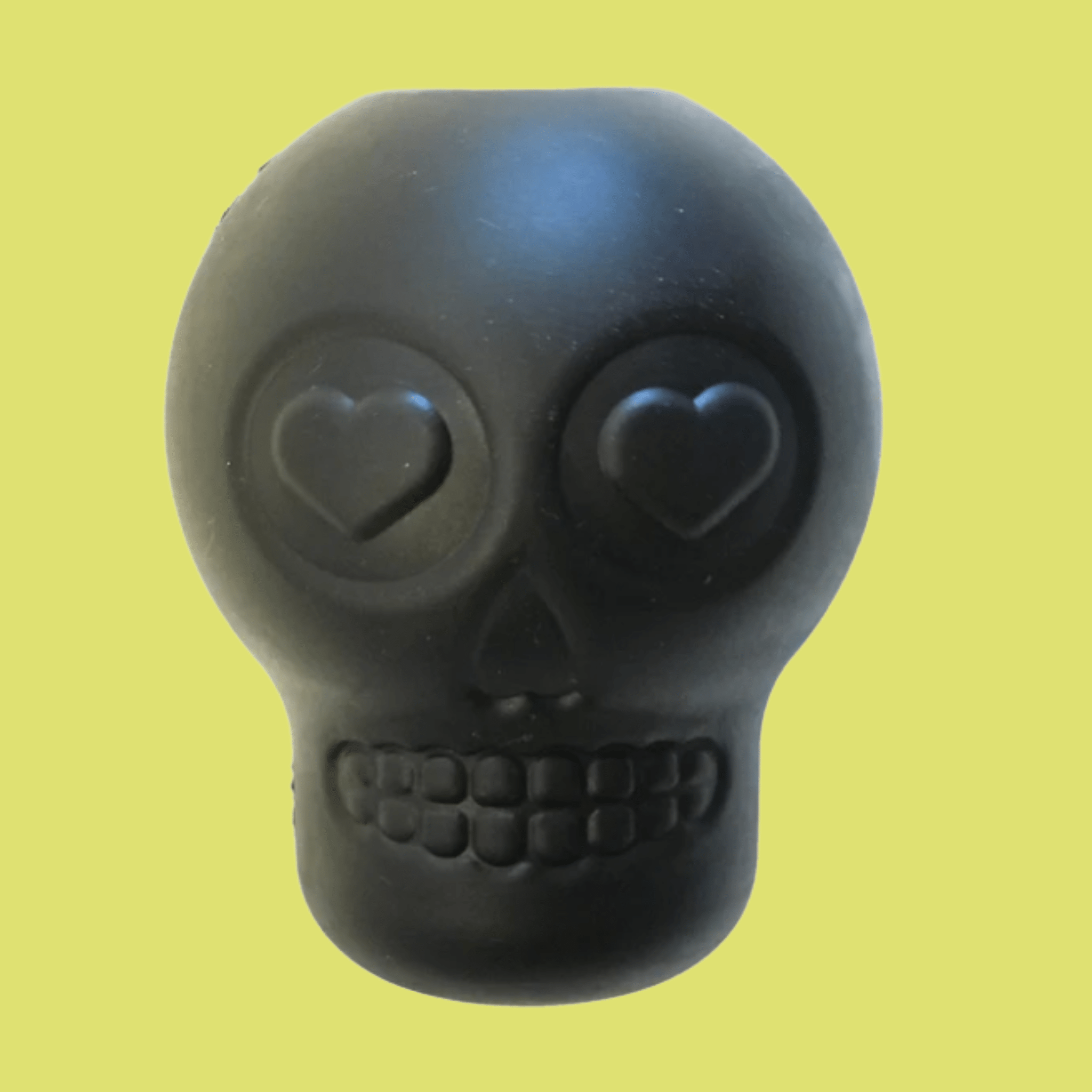 Farm to Pet Dog Treat Dispenser Black skull-shaped with heart eyes on a yellow background