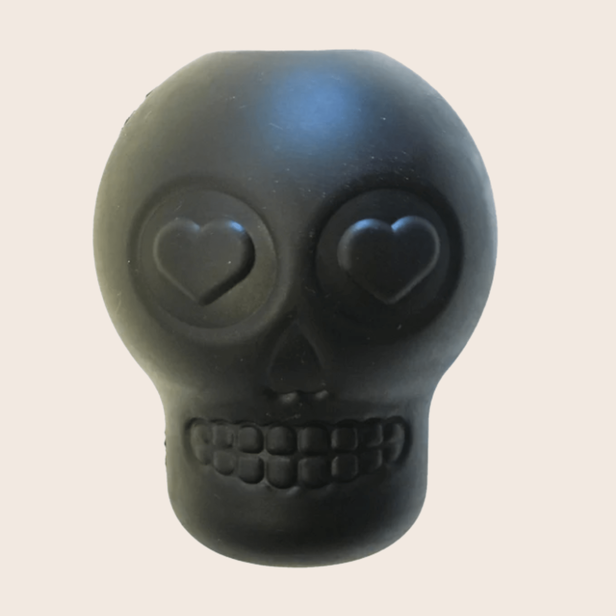 Black skull-shaped object with heart eyes on a beige background