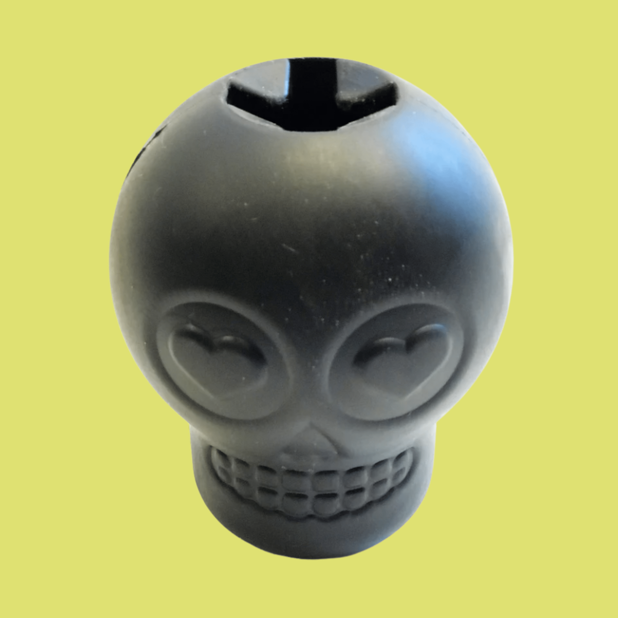 Farm to Pet Dog Treat Dispenser Black skull-shaped showing top view  on a yellow background