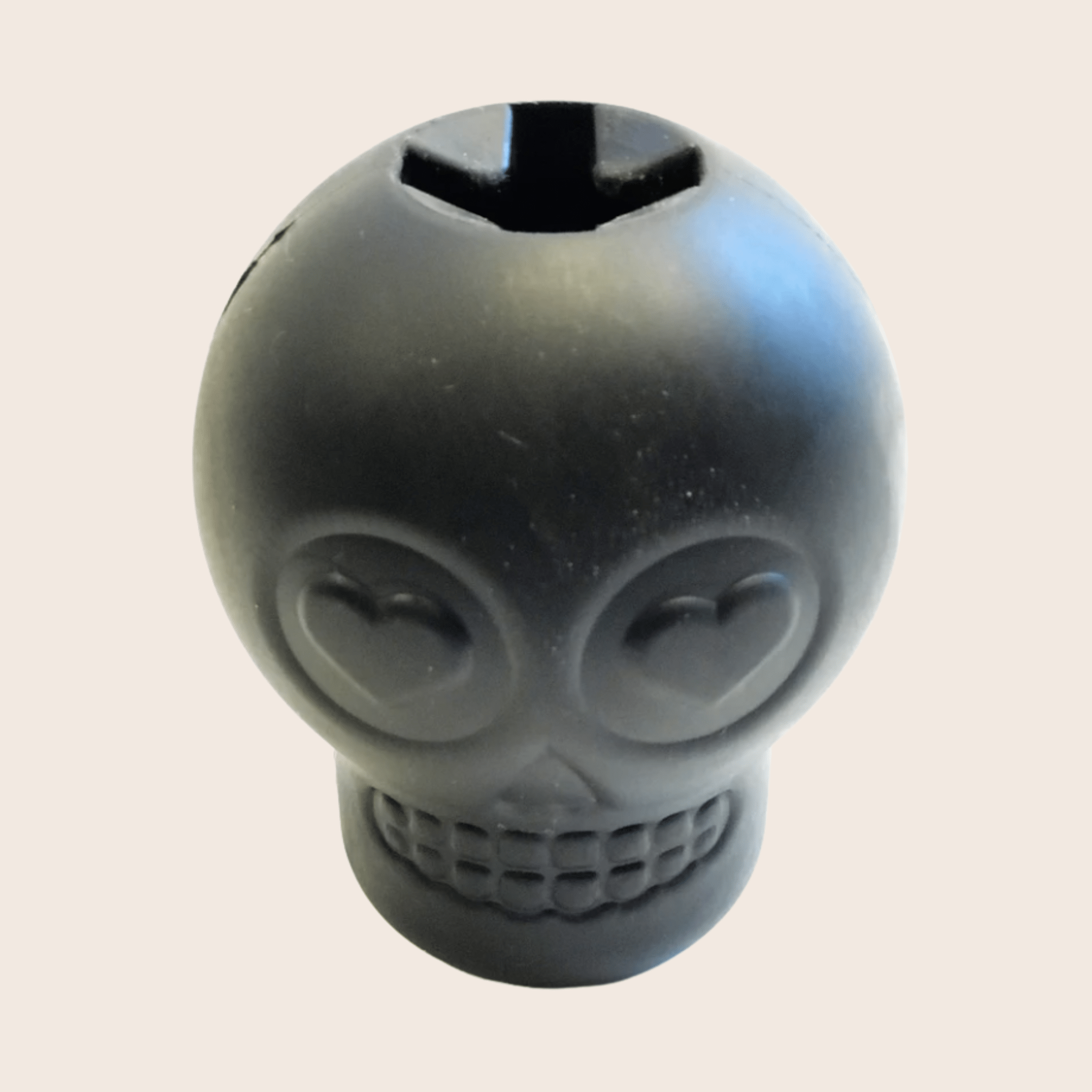 Black skull-shaped object on a beige background