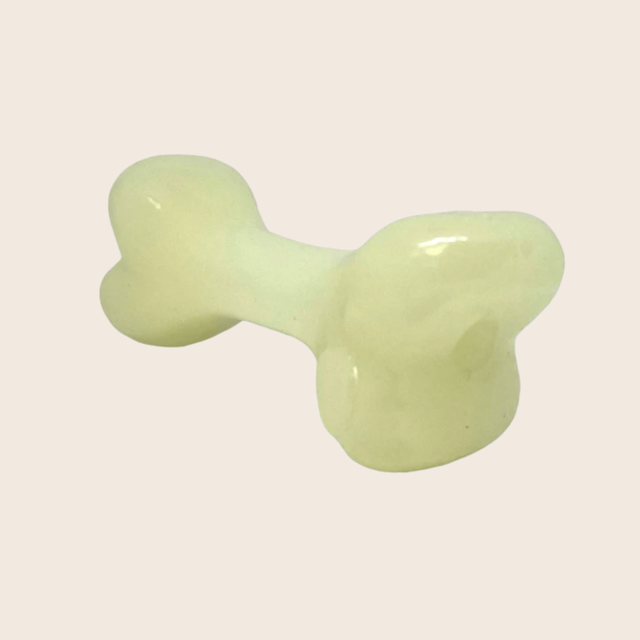 WHITE GLOW IN THE DARK bone-shaped object on a beige background