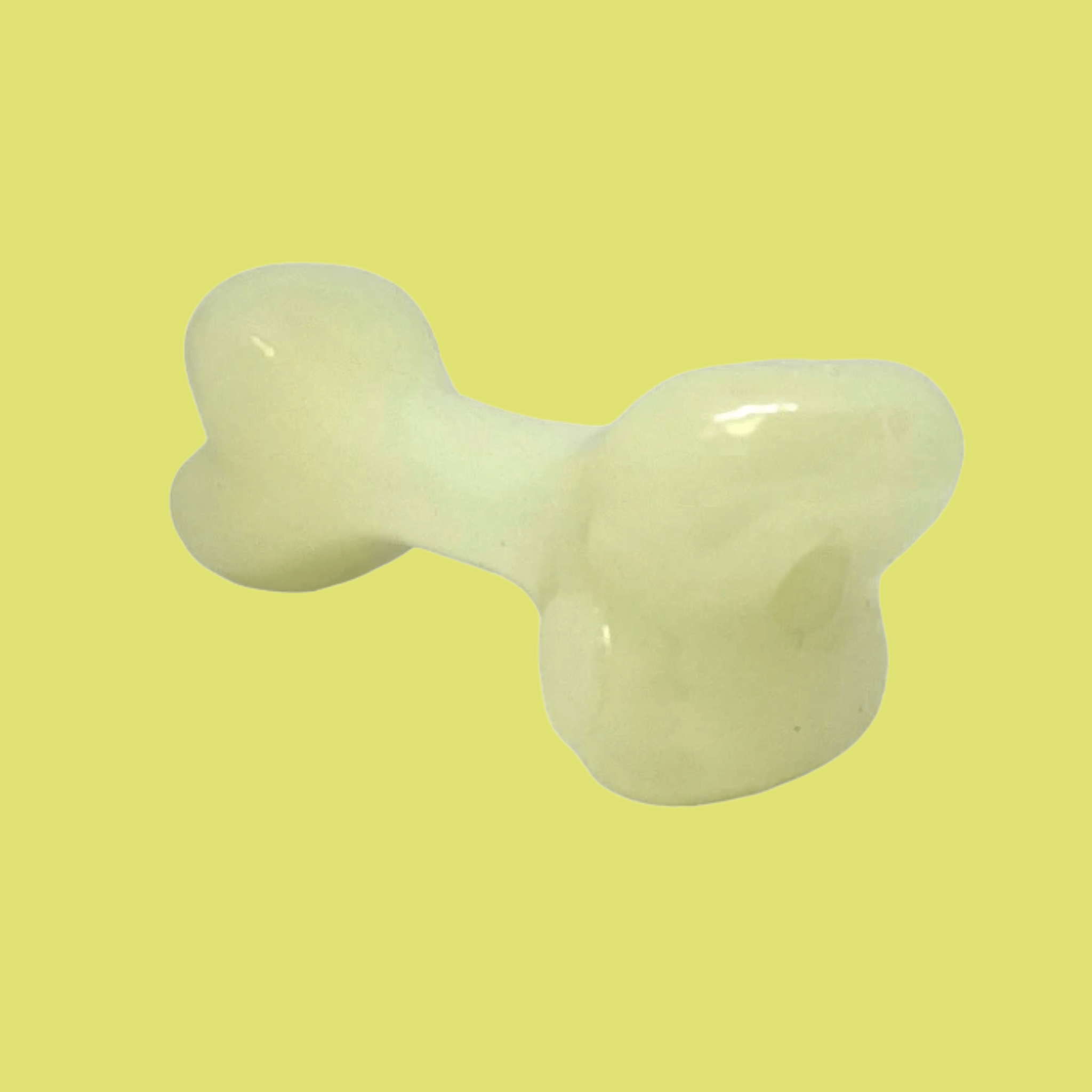 Farm to Pet Dog Treat Dispenser White bone that glows in the dark sideview on a yellow background.