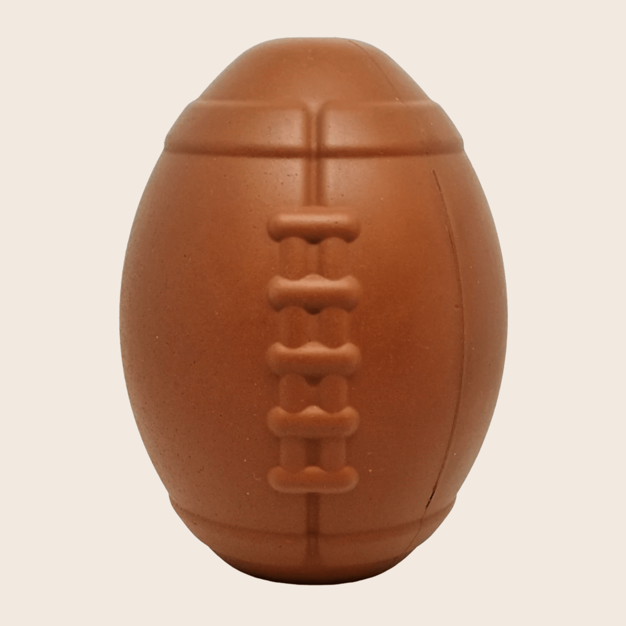 Farm to Pet Dog Treat Dispenser Brown football on a beige background.