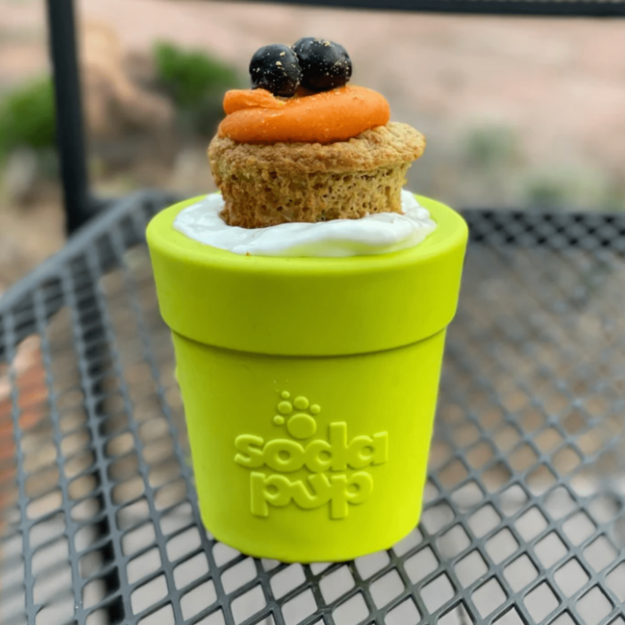 Farm to Pet Dog Food Dispenser a Green Flower pot with a small cupcake on top, sitting on a metal surface.