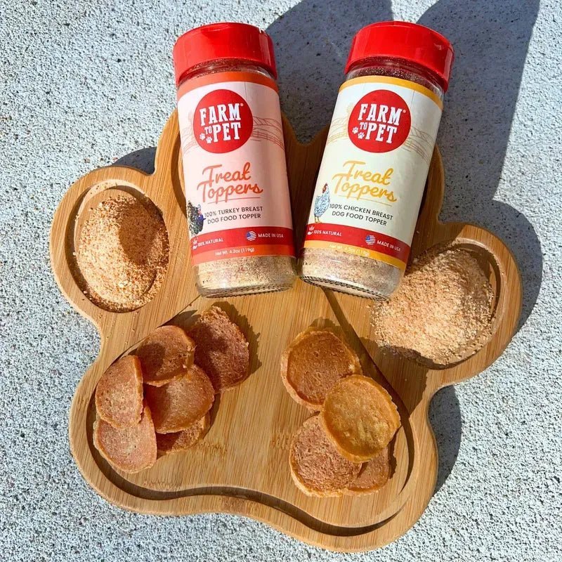 A wooden paw board and two jars with Farm to Pet Chicken Chips and  sprinkled with Chicken & Turkey Combo Topper Pack