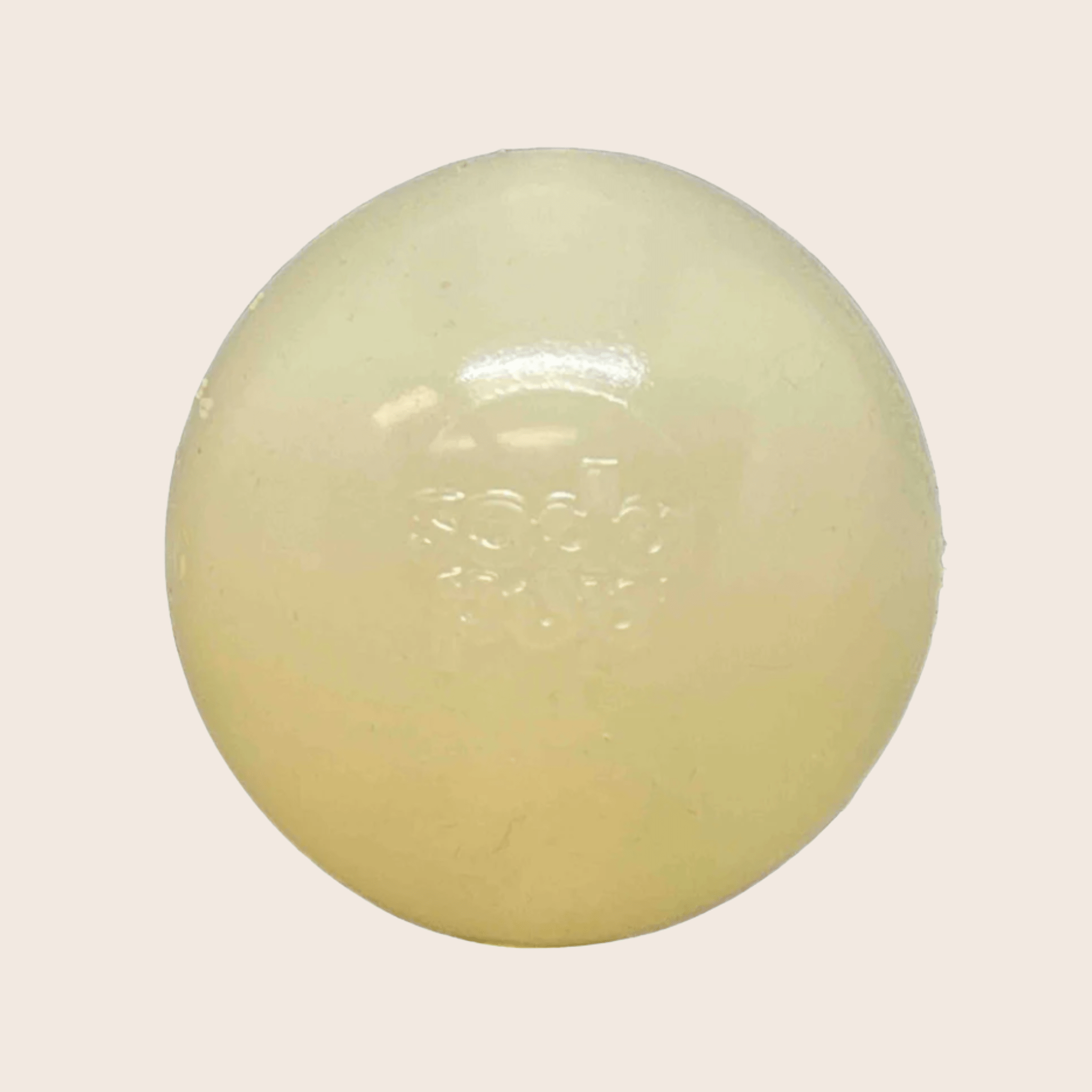 A Farm to Pet Dog Fetch Ball Glow-in the Dark Squeak ball is Round, white colored on a light beige background.