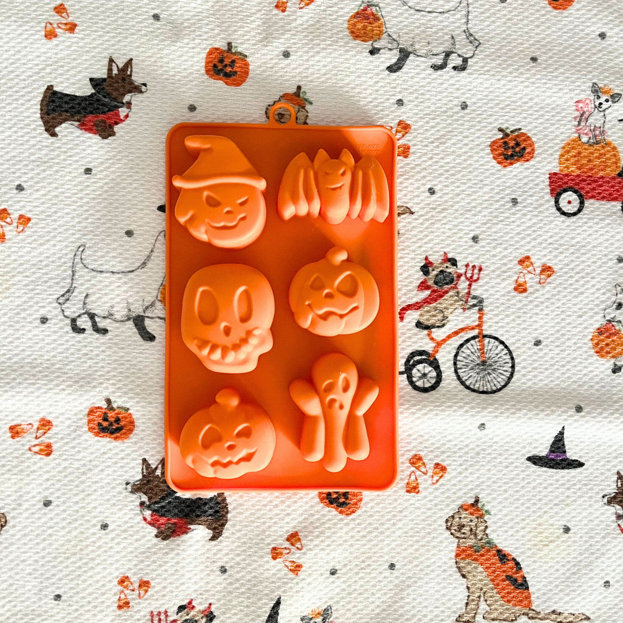 A Farm to Pet Halloween-themed orange silicone mold on a decorative paper background with pumpkins and ghosts.
