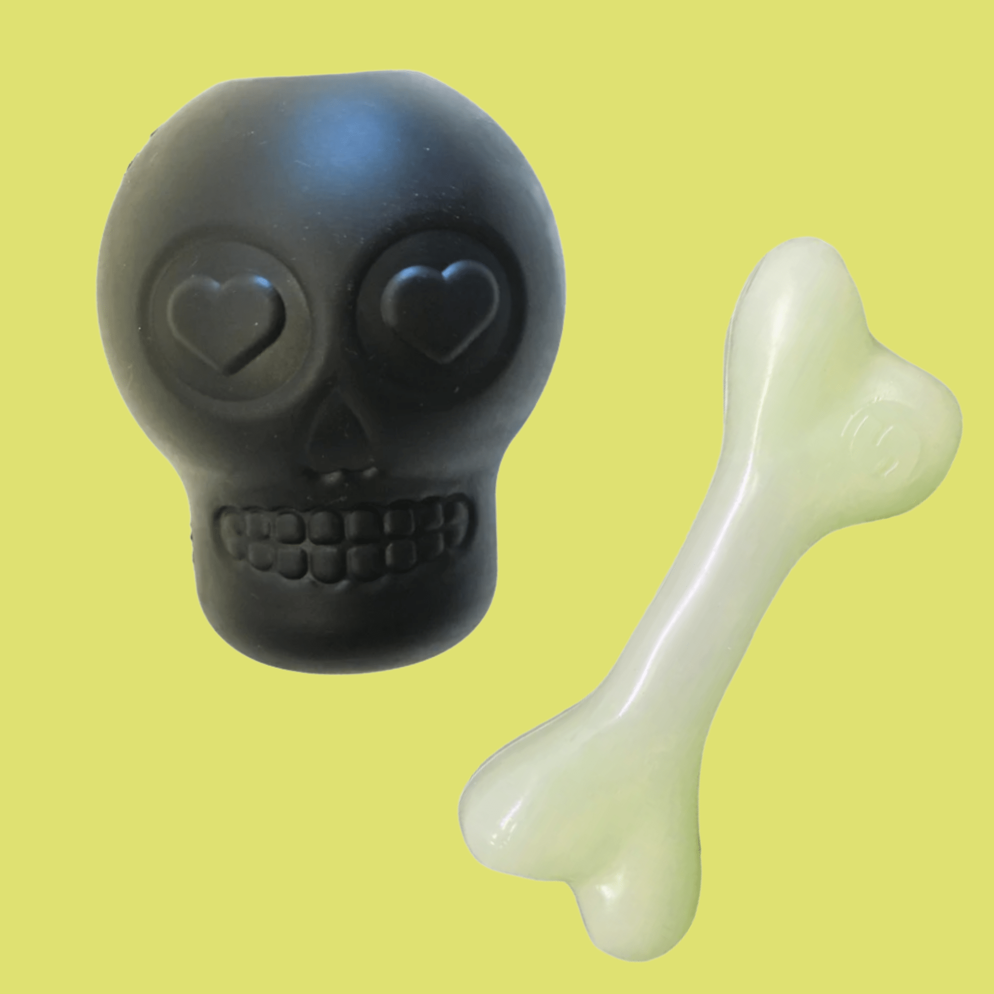 Farm to Pet Dog Treat Dispensers Black skull-shaped and white bone-shaped toy on a yellow background