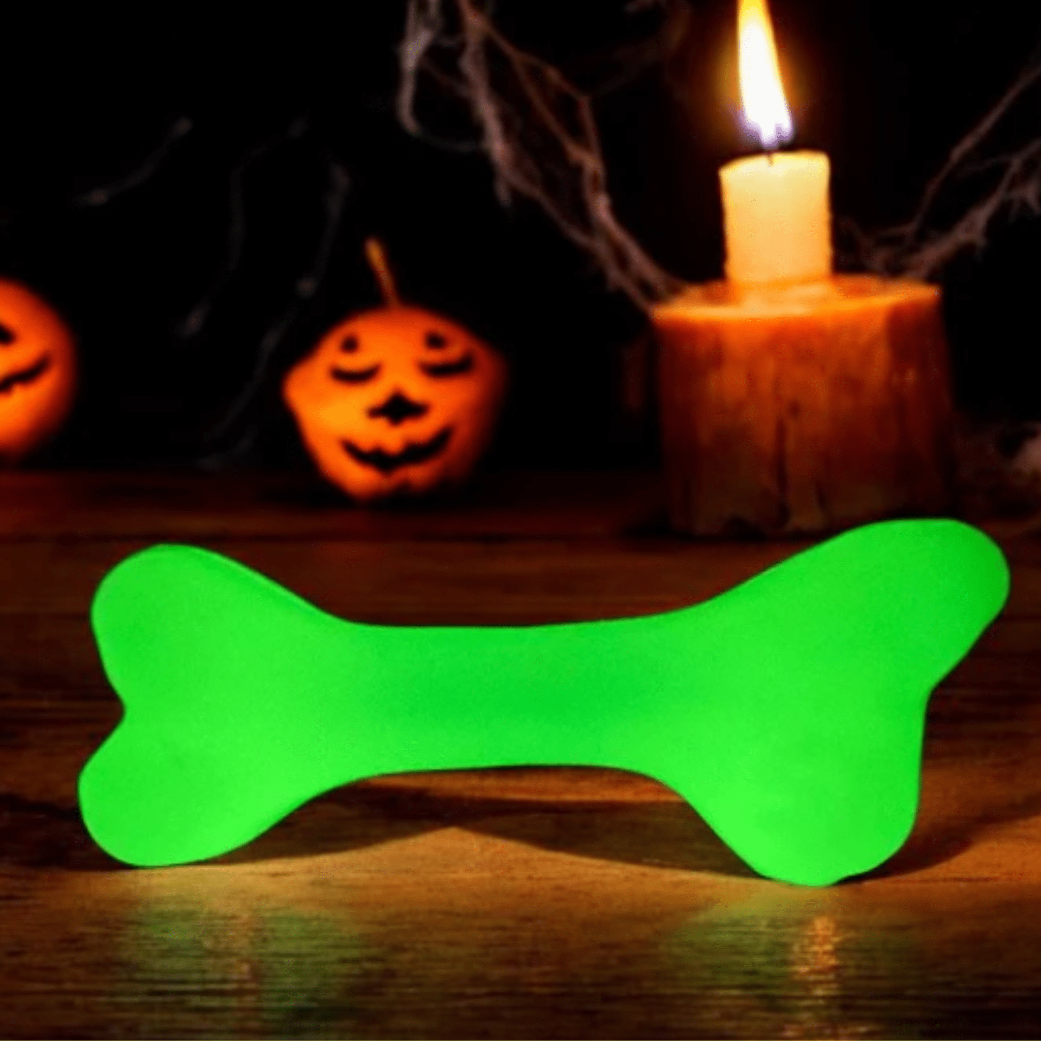 Farm to Pet Dog Treat Dispenser white bone that glows in dark Green  on a wooden surface with Halloween decorations in the background.
