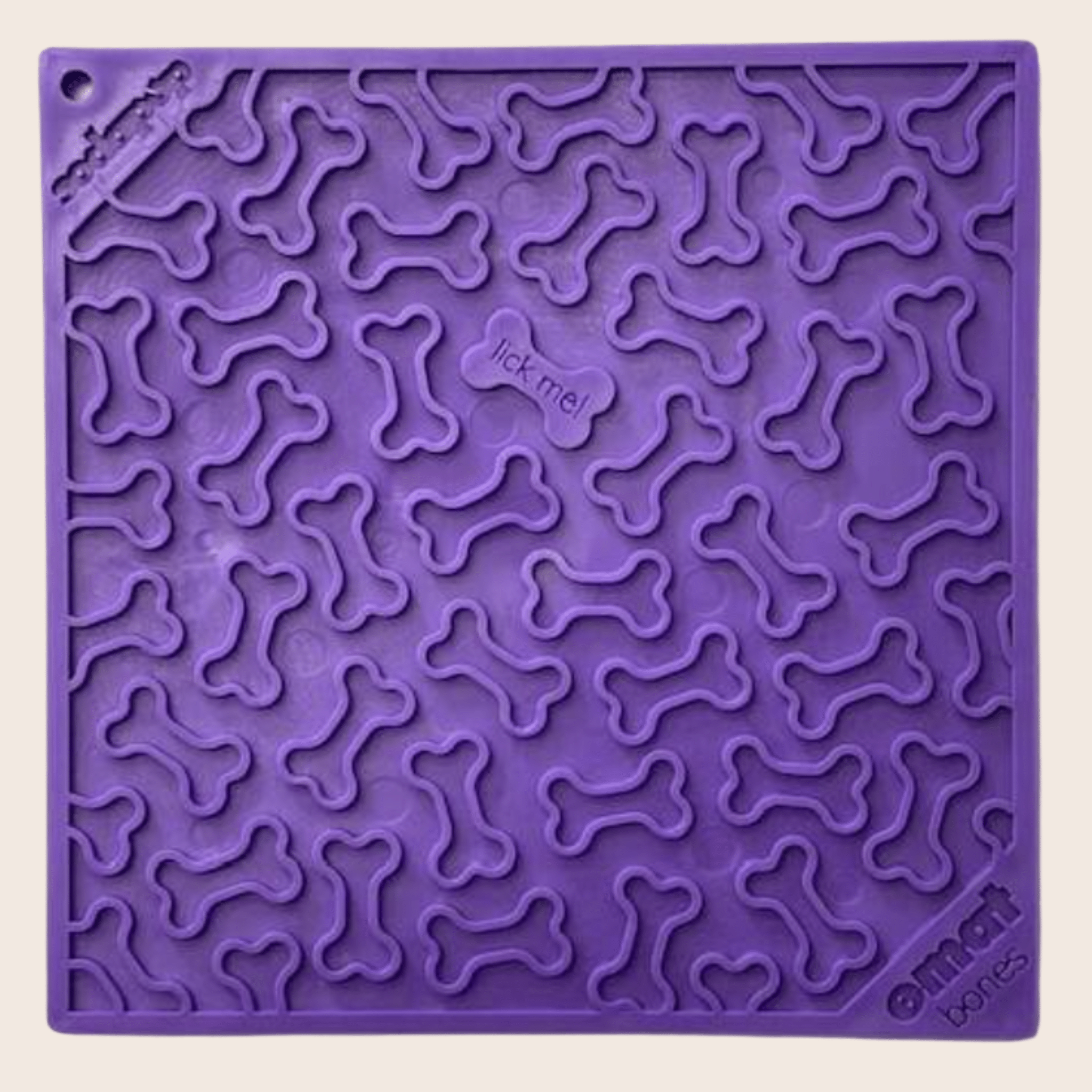 A Farm to Pet Purple dog bone lick mat with bone patterns and 'lick me!' text on a beige background.