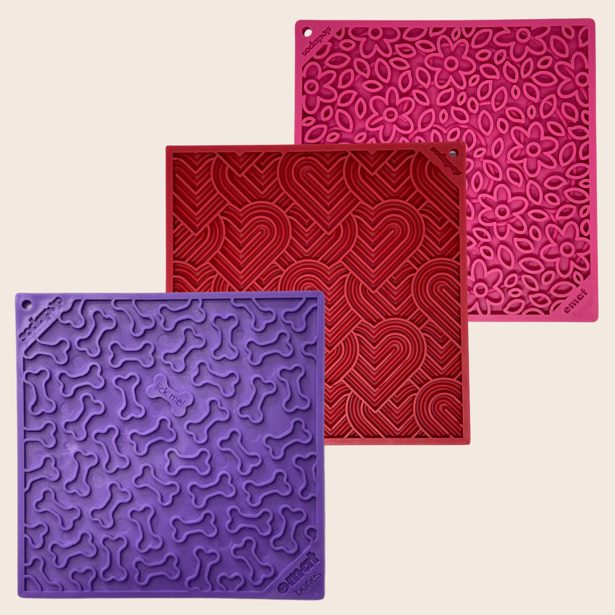 Farm to Pet Dog Lick Mats Three silicone mats in purple, red, and pink with textured patterns on a beige background.