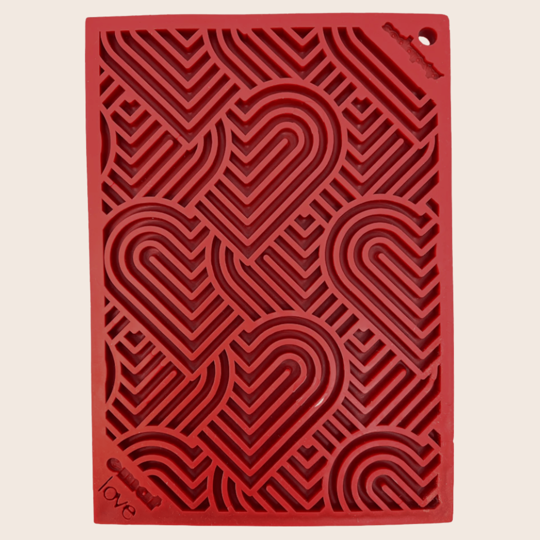 A Farm to Pet Red Hearts Lick Mat  textured with heart pattern on a beige background.