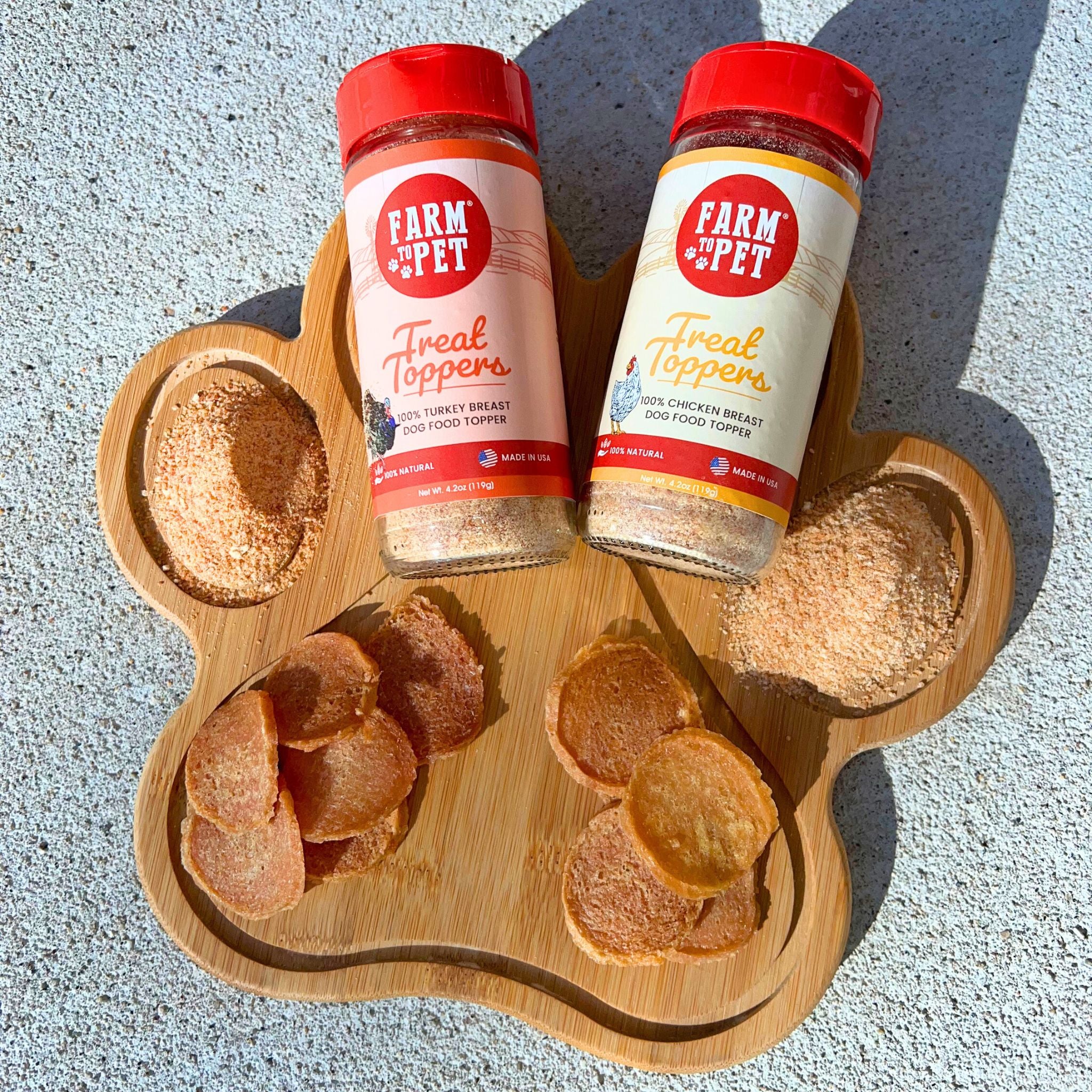 Two gloss jars and a wooden board shaped like a paw with chicken chips and sprinkled with Farm to Pet chicken and Turkey Combo Toppers Pack.