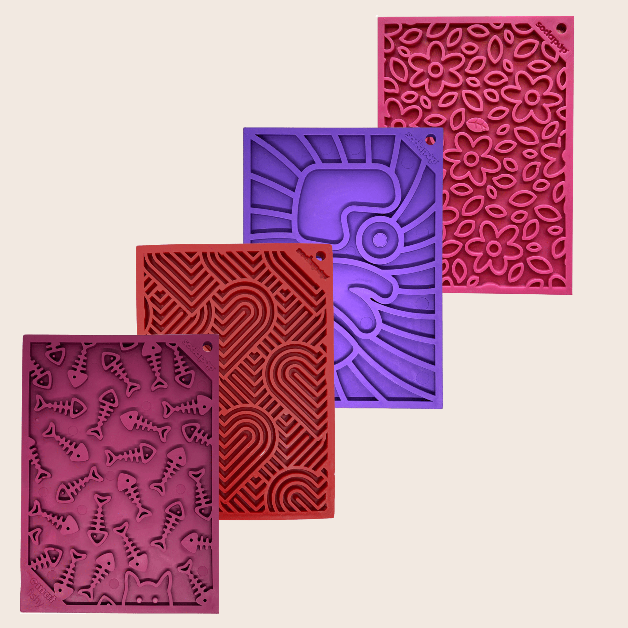 Four textured silicone lick mats from Farm to Pet in maroon, purple, red, and pink on a beige background.