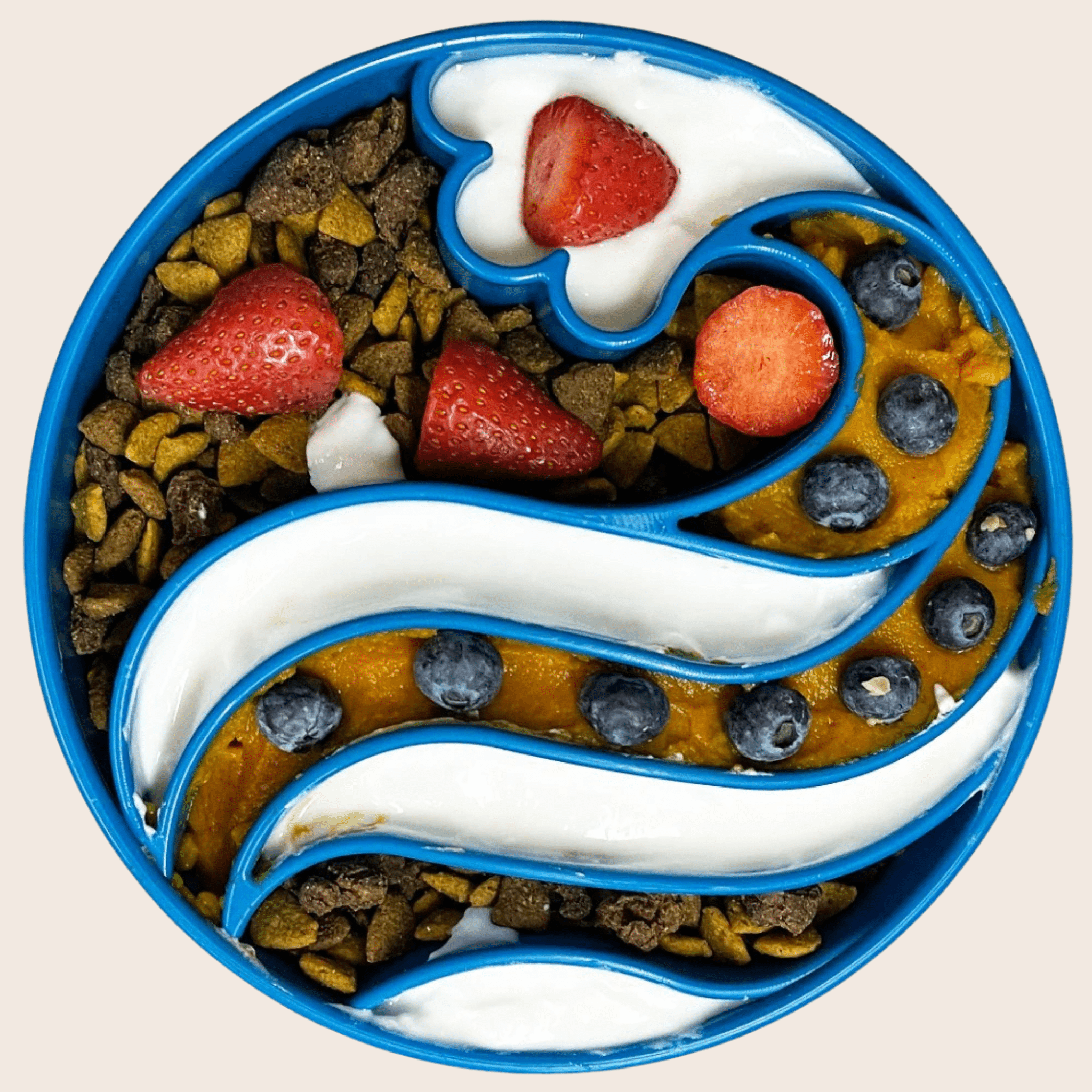  A colorful Farm to Pet Slow Feeder Dog Bowl in blue wave pattern. The bowl is filled with yogurt, strawberries, and blueberries arranged in a decorative pattern. 
