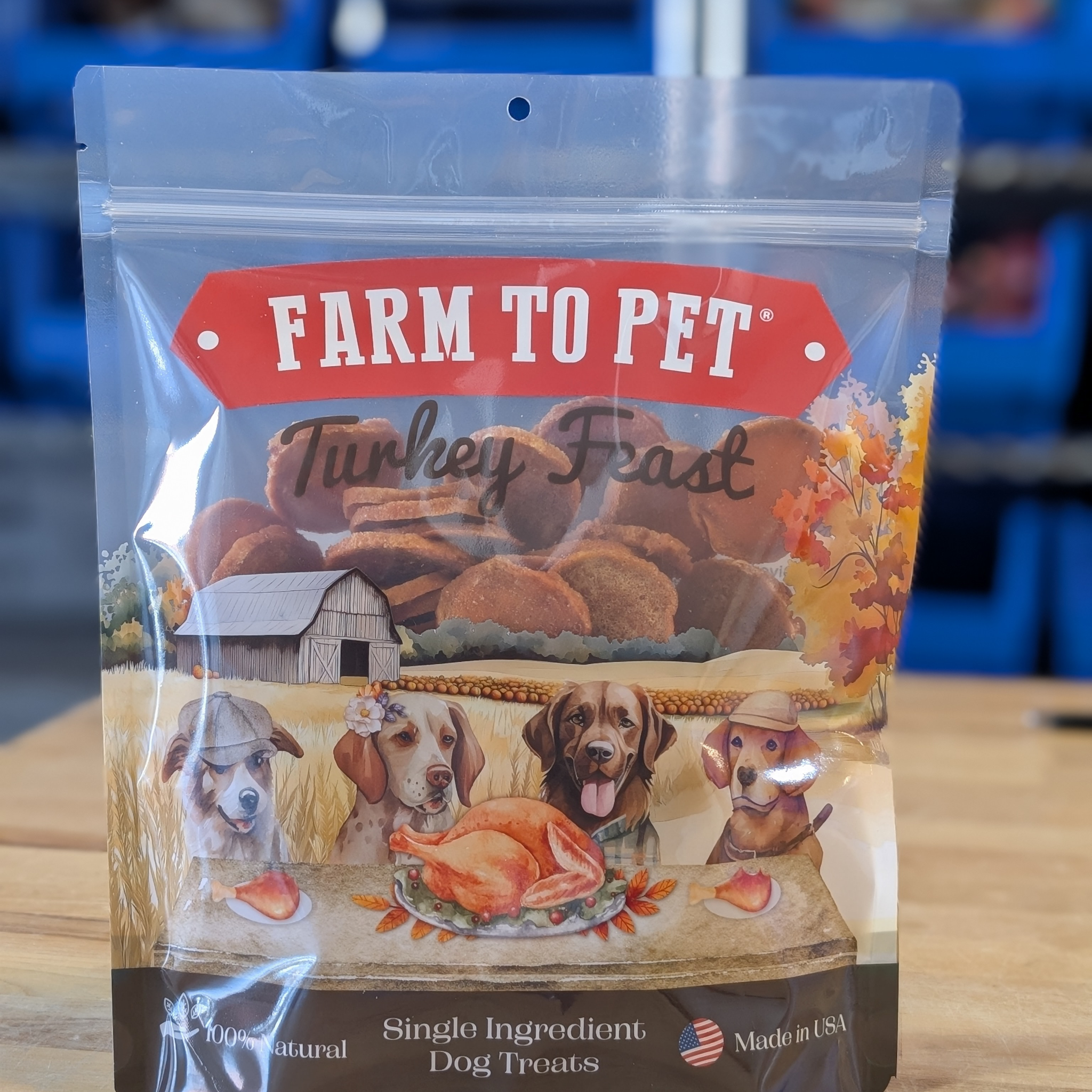 A package of Farm to Pet Turkey Feast dog treats on a wooden surface with a blurred background.