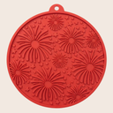 Red silicone lick mat with firework pattern on a beige background