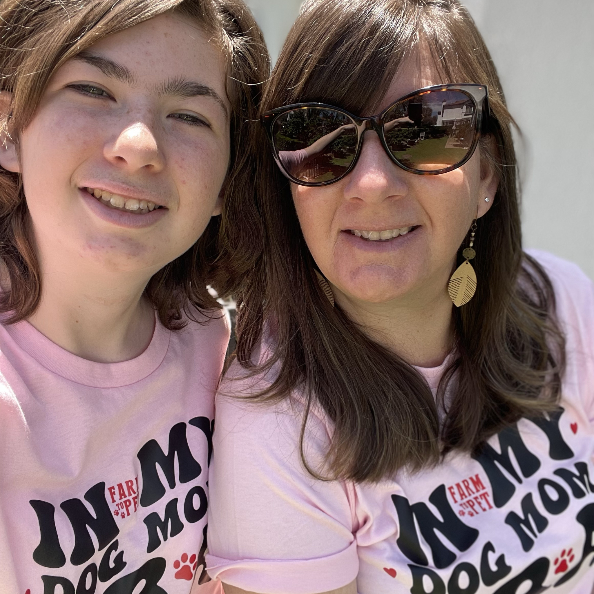 Two people wearing matching pink t-shirts with text and graphics.