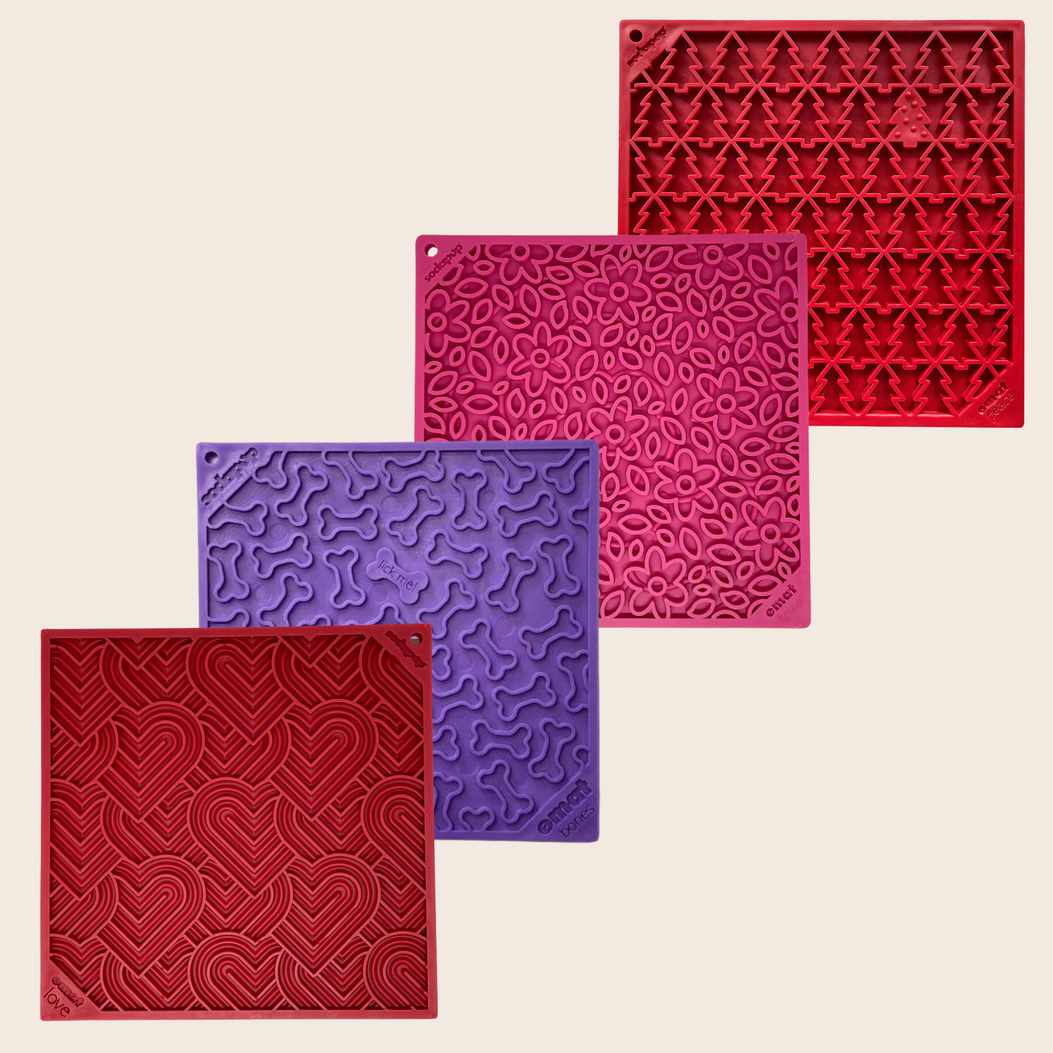 Four textured square lick mats in red, purple, and pink on a beige background