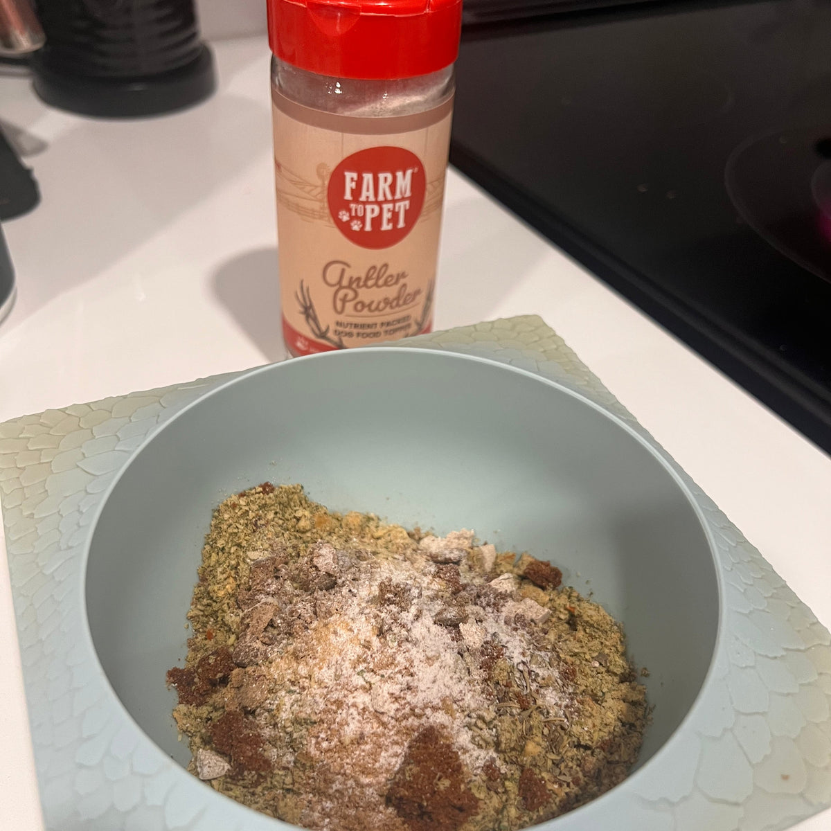 Antler Powder dog food topper sprinkled over a bowl of dog food, an elk antler supplement