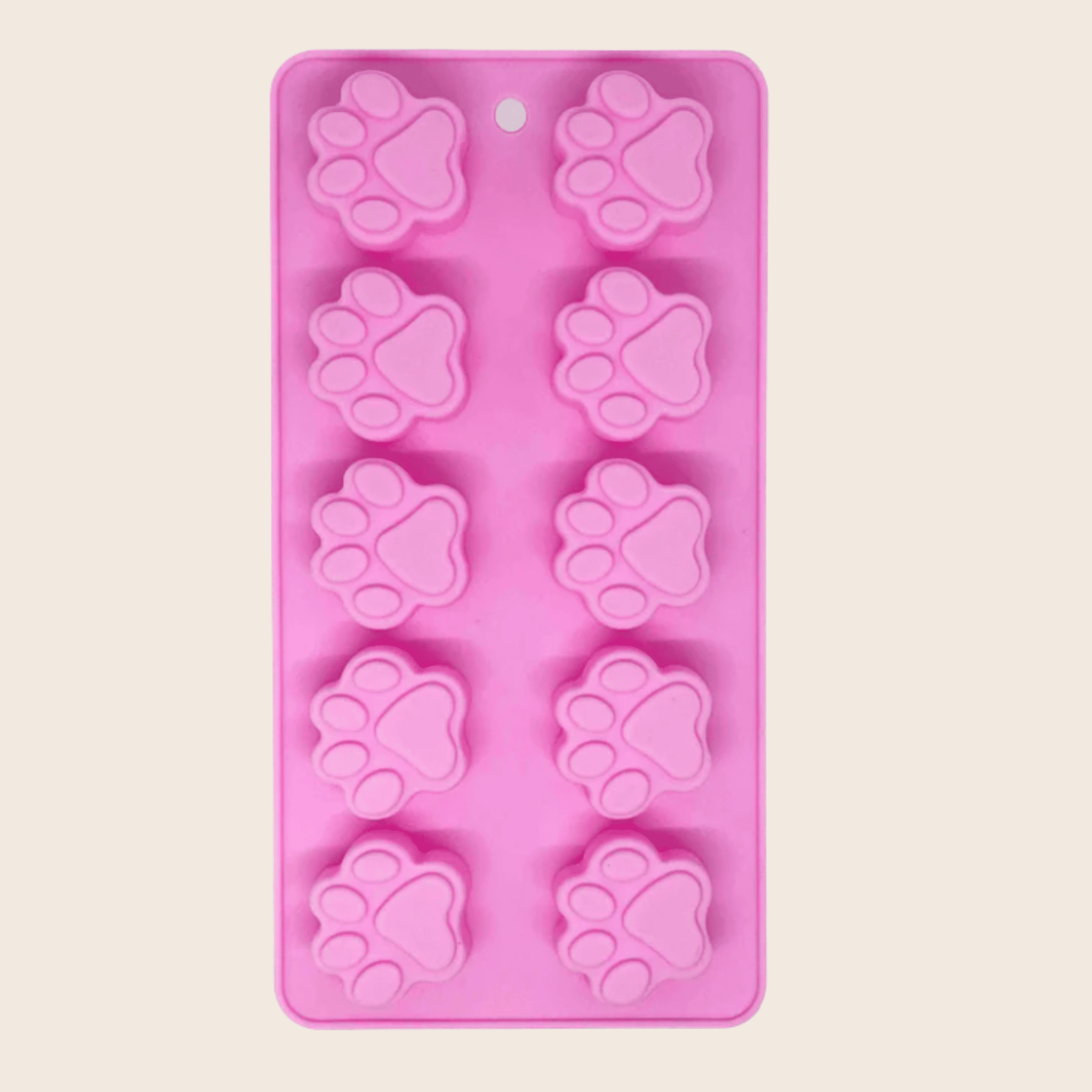 Pink silicone mold with paw prints on a beige background
